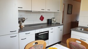 Una cocina compacta con armarios blancos, horno empotrado y cafetera.