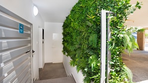 A hallway with a vertical garden wall, a door with a sign, and a staircase.