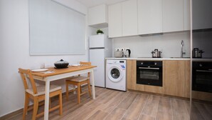 A compact kitchen with a washing machine, oven, and a dining area with a table and chairs.