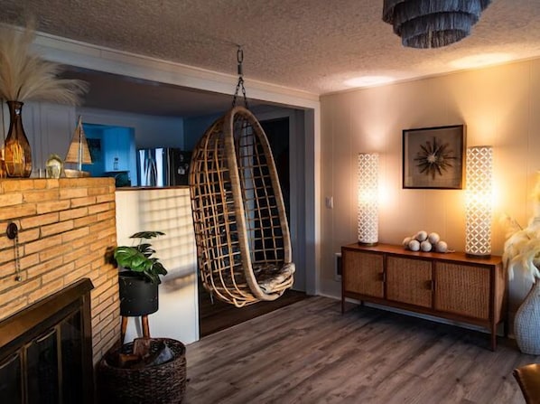Un salon chaleureux avec un fauteuil suspendu, une cheminée et un meuble en bois.