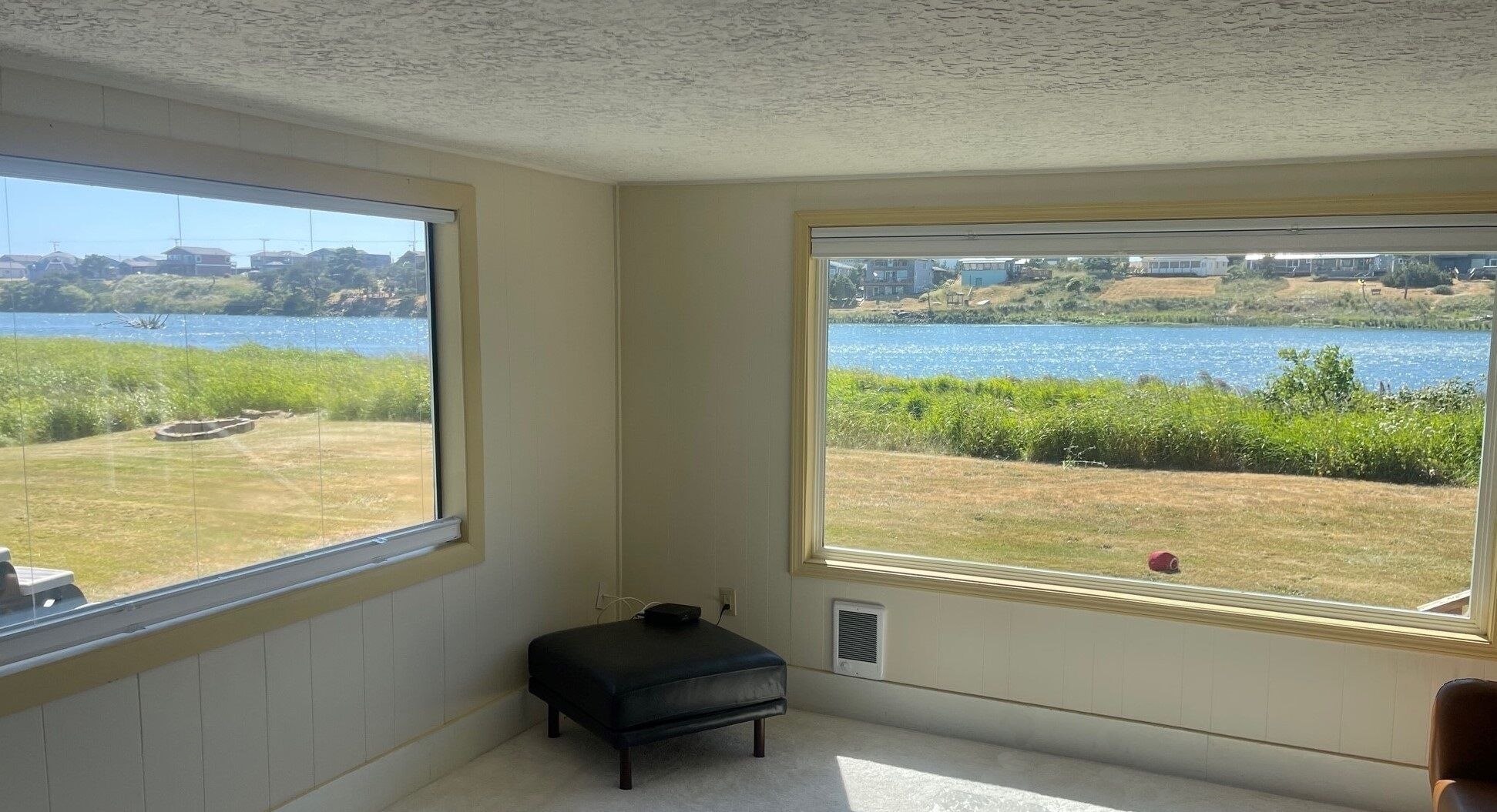 Habitación con ventanas amplias que ofrecen vistas a un lago y follaje circundante.