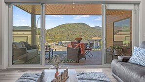 A modern living room with a large sliding glass door leading to an outdoor patio area.