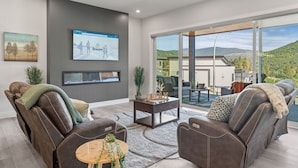 A modern living room with a reclining leather sofa, a coffee table, and a large TV screen displaying a webpage.