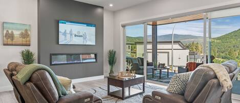 A modern living room with a reclining leather sofa, a coffee table, and a large TV screen displaying a webpage.
