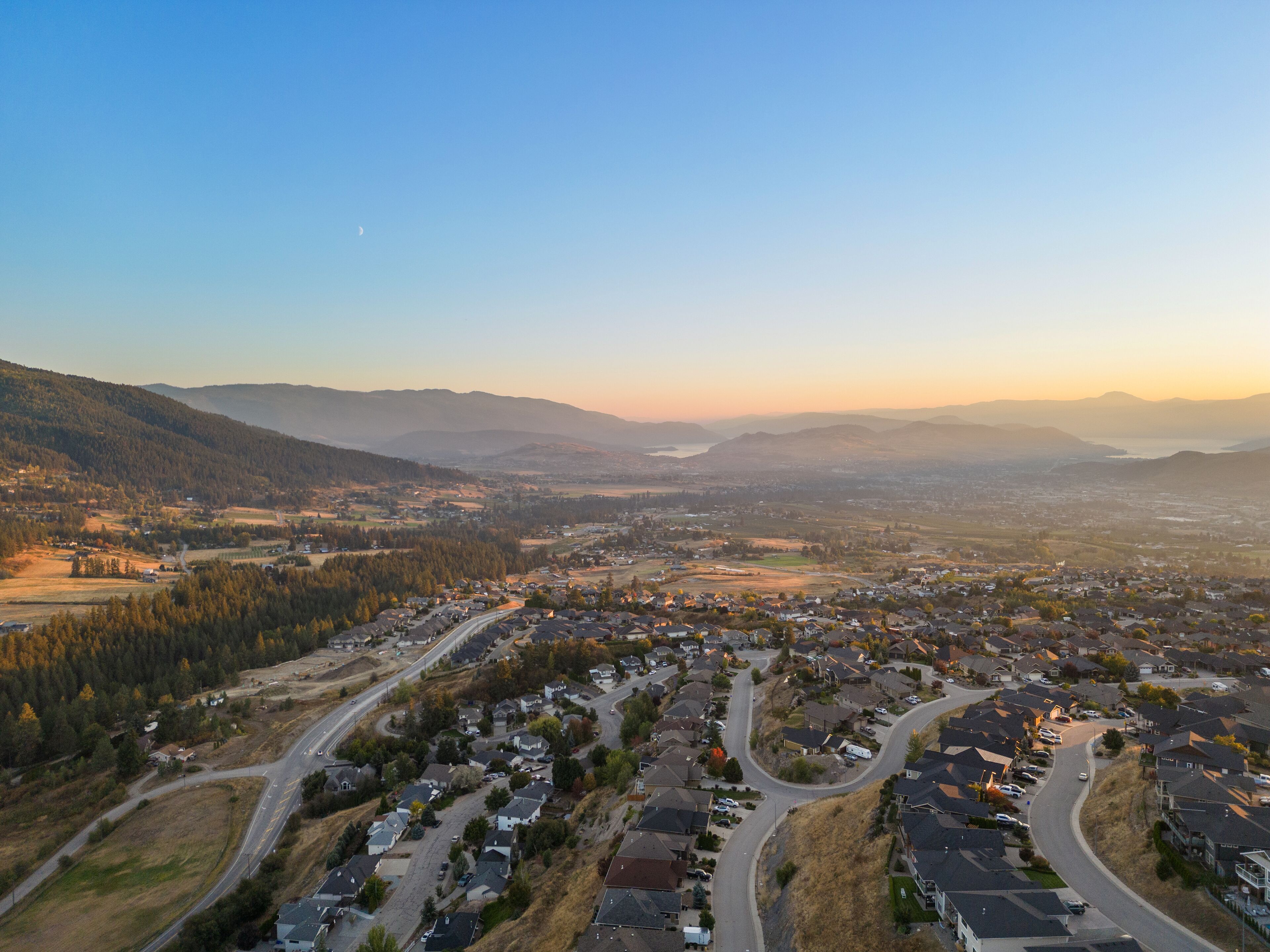 Zona residencial amb cases, carreteres i un paisatge de muntanyes al fons.