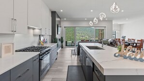 A modern kitchen with a central island, stainless steel appliances, and a view to the outdoors.