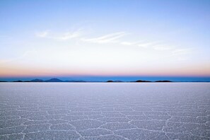 A vast salt flat with a clear sky and distant mountains.