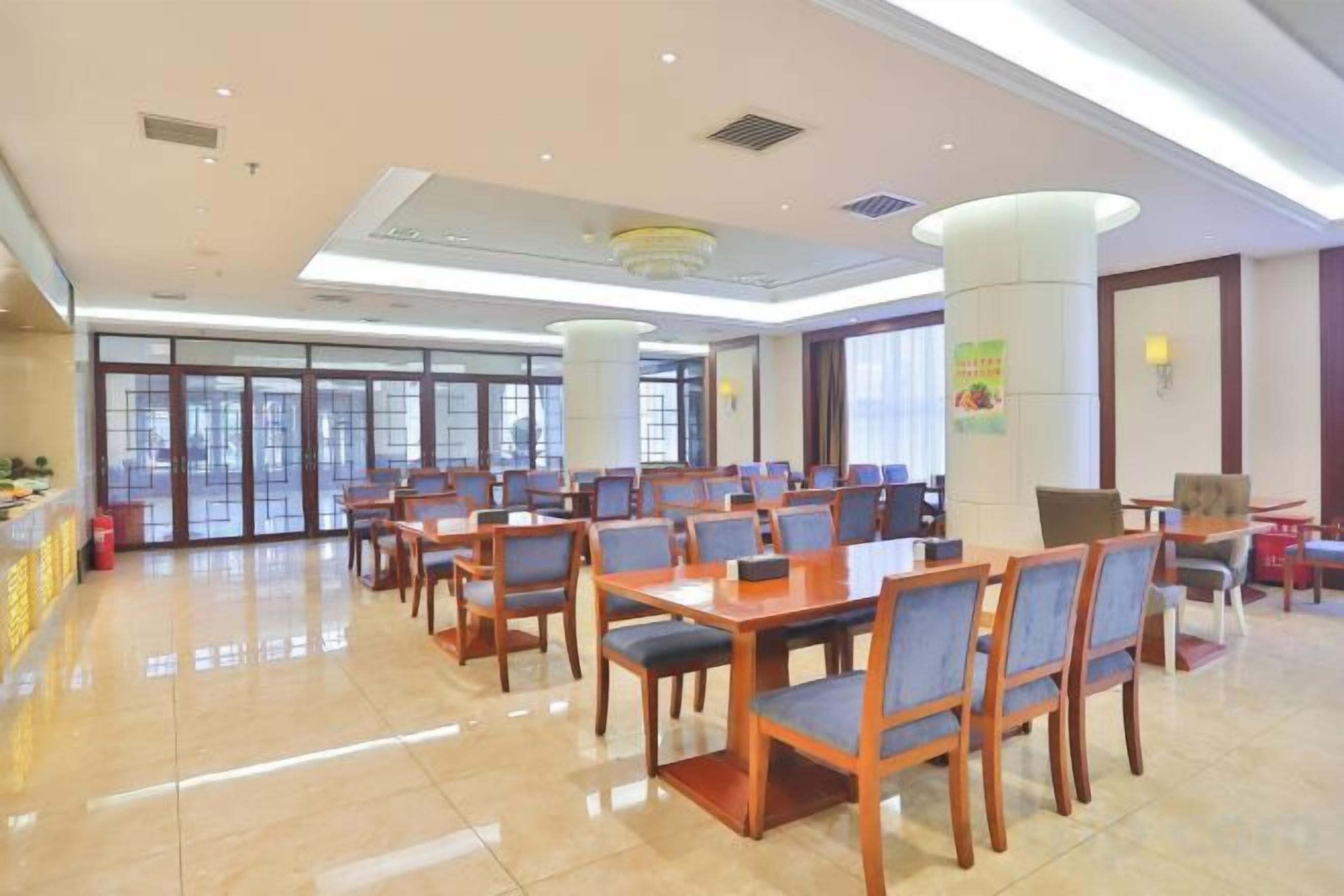 A spacious indoor area with multiple tables and chairs, large windows, and a reception desk.
