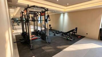 A gym with exercise equipment, a mirror, and a black mat.