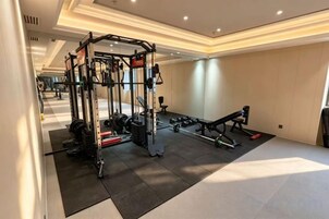 A gym with exercise equipment, a mirror, and a black mat.