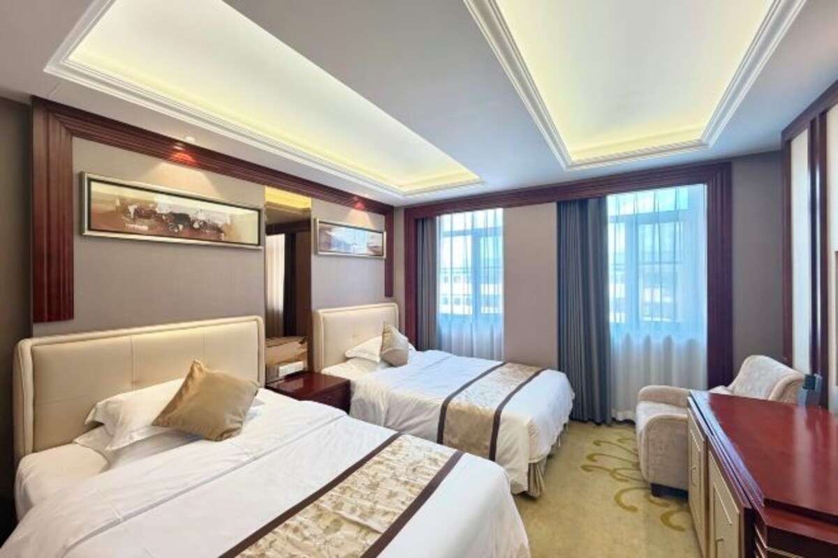 A hotel room with two beds, a desk, and a chair.