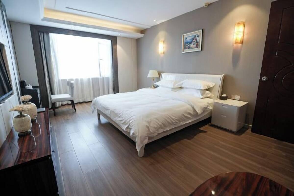 A modern hotel room with a large bed, bedside tables, a desk, and a chair.
