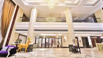 A hotel lobby with a grand chandelier, a reception desk, and a statue of a deer.