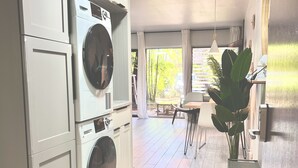Une cuisine moderne dotée d’appareils électroménagers intégrés, un coin repas baigné de lumière naturelle et une vue sur la verdure environnante.