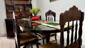 A dining area with a wooden table and chairs, a painting on the wall, and a bookshelf in the background. - Casa Nawi (Cali)