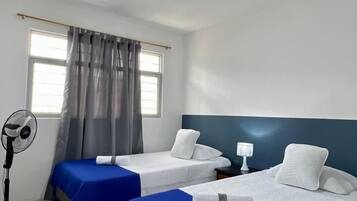 Habitación de hotel con dos camas, un ventilador y una ventana con cortinas.