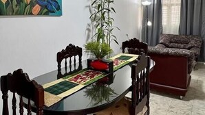 A dining area with a table, chairs, a painting, a plant, and a sofa. - Casa Nawi (Cali)