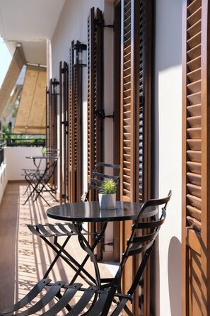 Ein Balkon mit Tisch, Stühlen, Holzläden und einem Blumentopf.