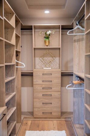 Ein begehbarer Kleiderschrank mit Holzböden, einer zentralen Schubladenleiste und einer Kleiderstange.