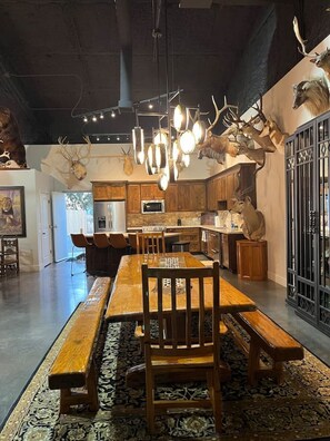 Un coin repas avec une table et des bancs en bois, un tapis à motifs et des décorations en forme de bois de cerf sur les murs.