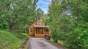 A rustic cabin with a stone chimney, wooden porch, and a stone pathway leading to the entrance. - Enjoy this cozy home with a wrap around porch, near the Smoky Mountains (Townsend)