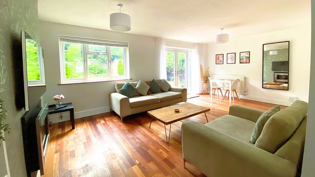 A spacious living room with hardwood flooring, a sofa, a coffee table, and a dining area with a table and chairs.