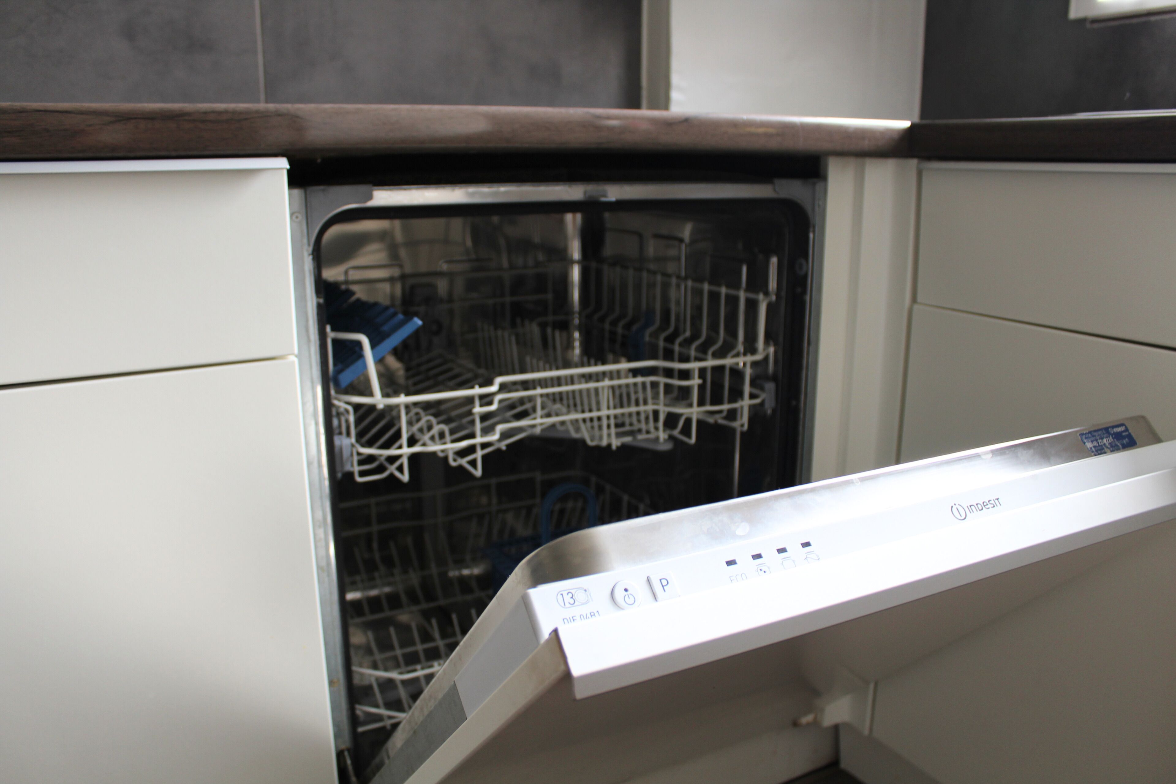 A dishwasher with a control panel and a partially loaded rack.