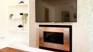 A modern living room with a flat-screen TV mounted above a built-in fireplace.