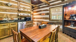 A rustic kitchen with wooden walls, a wooden dining table, and basic appliances. - Glasgow Getaway w/ Patio, Fireplace & Grill! (Glasgow)