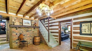 A rustic interior with a wooden staircase, brick walls, and a chandelier. - Glasgow Getaway w/ Patio, Fireplace & Grill! (Glasgow)