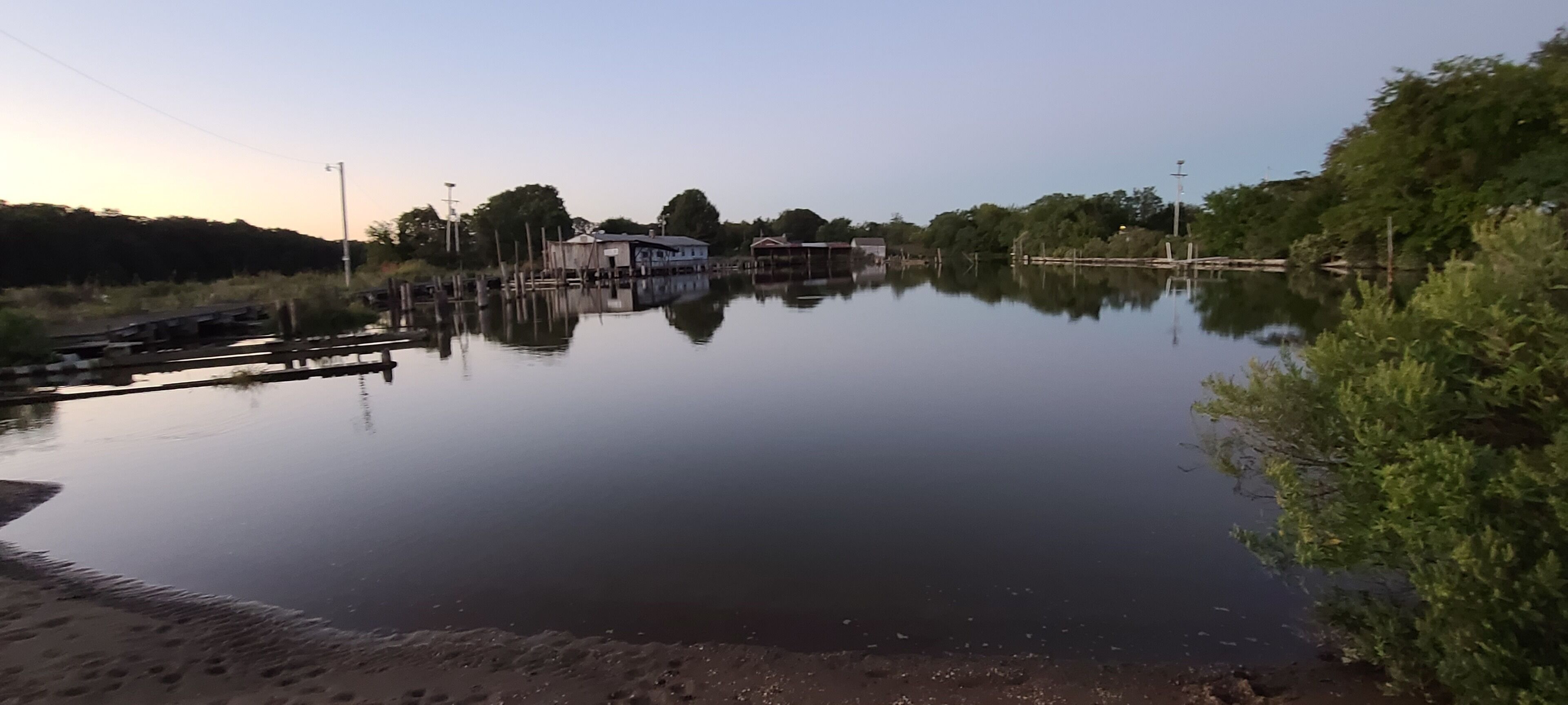 Un lac paisible, avec un quai et des bâtiments en arrière-plan.