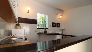 Una cocina moderna con encimera de madera, pileta de acero inoxidable y ventana con vista a follaje.