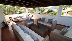 Un espacio al aire libre cubierto con mobiliario de mimbre, una mesa de centro y una planta en maceta.