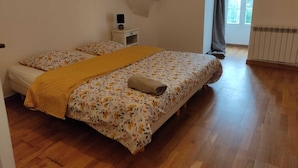 Un dormitorio con dos camas, una mesita de noche, un radiador y una ventana con cortinas.