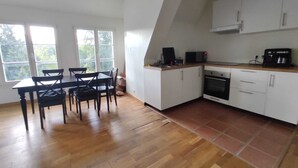 Una cocina con gabinetes blancos, encimera de madera y un comedor con mesa y sillas.