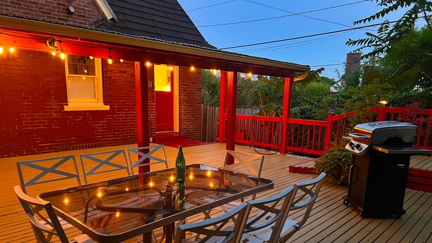 A deck with a glass table and chairs, a barbecue grill, and a red railing. - Ballard Brick Tudor • A/C • Dog-Friendly (Seattle)