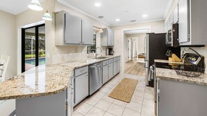 A modern kitchen with granite countertops, stainless steel appliances, and a view to the outside. - Billiards and Poolside Bliss Centrally located in SE Cape Coral, Pet Friendly! (Cape Coral)
