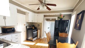 A modern kitchen with white cabinets, a black refrigerator, a stove, and a dining area with a wooden table and chairs. - Single level 3 bedroom, fenced yard, central air (Auburn)