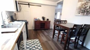 Une cuisine compacte avec un coin repas, un plancher en bois et un petit tapis.