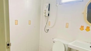 Une petite salle de bain simple, équipée d’un WC, d’un lavabo et d’une douche.