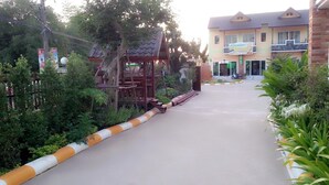 Un chemin menant à un bâtiment doté d’une entrée couverte et d’un balcon.