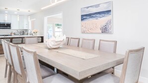 A modern dining room with a large wooden table, six chairs, and a decorative centerpiece.