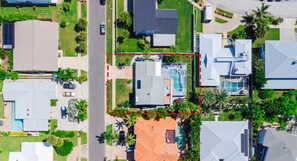 Vue aérienne d’un quartier résidentiel avec des maisons, une piscine et une zone délimitée par des barrières, indiquée par des lignes pointillées rouges.