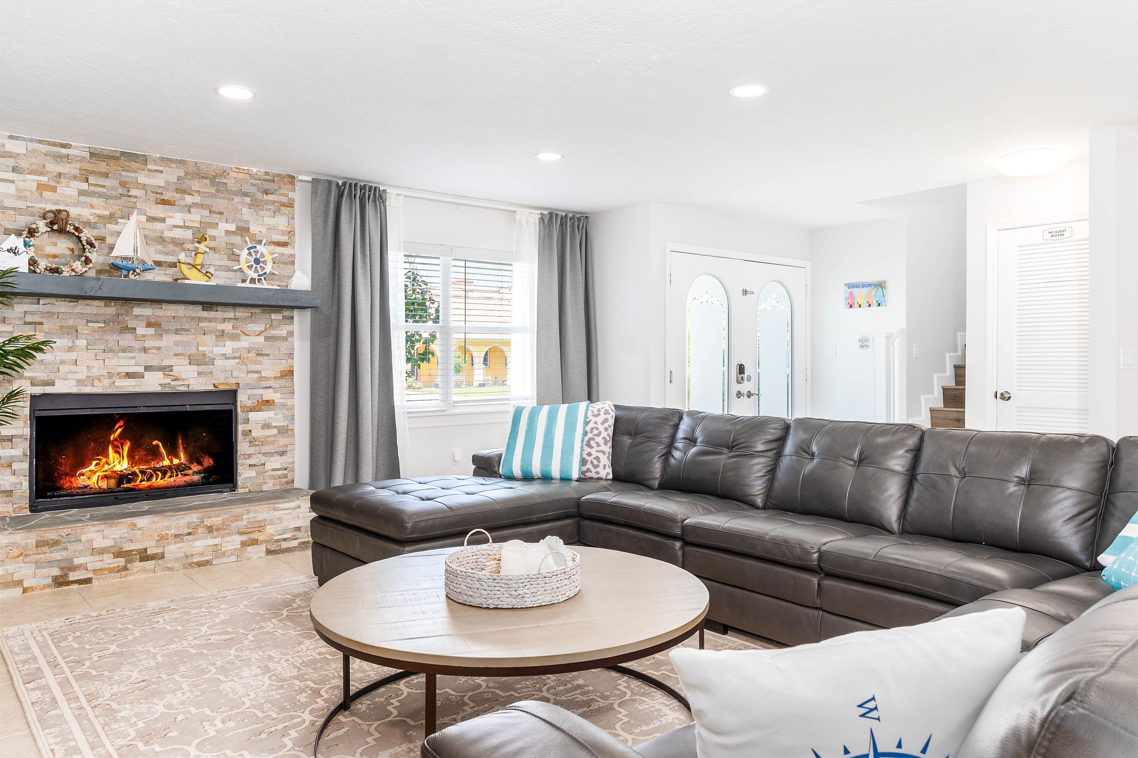 A living room with a fireplace, leather sofa, and a round coffee table.