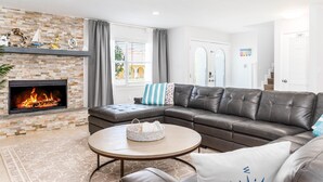 A living room with a fireplace, leather sofa, and a round coffee table.