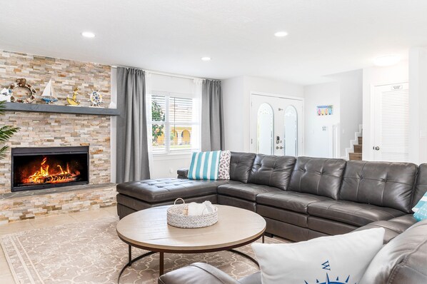 A living room with a fireplace, leather sofa, and a round coffee table.
