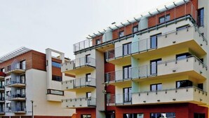 Un edifici residencial de diverses plantes amb balcons, un pati central i façanes combinades de maó i estuc.