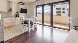 Un apartament modern amb zona de dinar, cuina i grans portes corredisses de vidre que donen a un balcó.