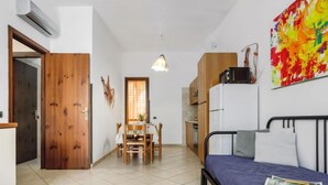A compact room with a bed, a dining table, and a kitchenette. - Acquamarina Gaia by Interhome (San Vito lo Capo)