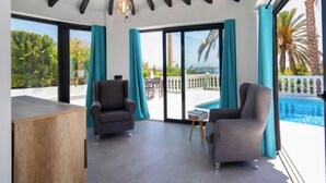 A modern room with a pool, two armchairs, and a ceiling with black beams and a hanging light fixture. - Estrella Azul by Interhome (Calpe/Calp)